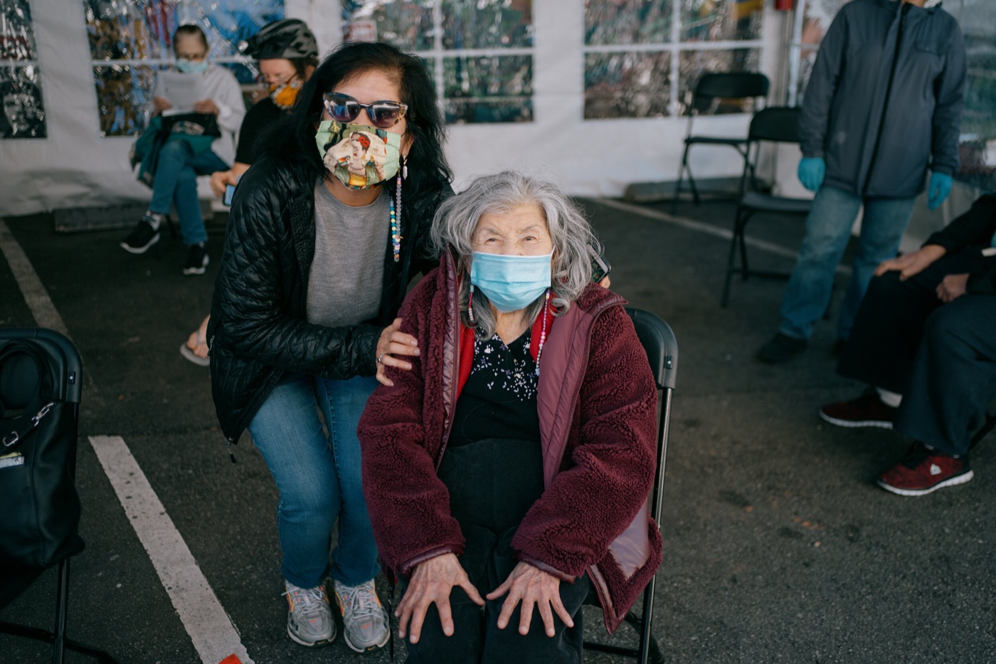 An older woman and her daughter wait together in a vaccination tent